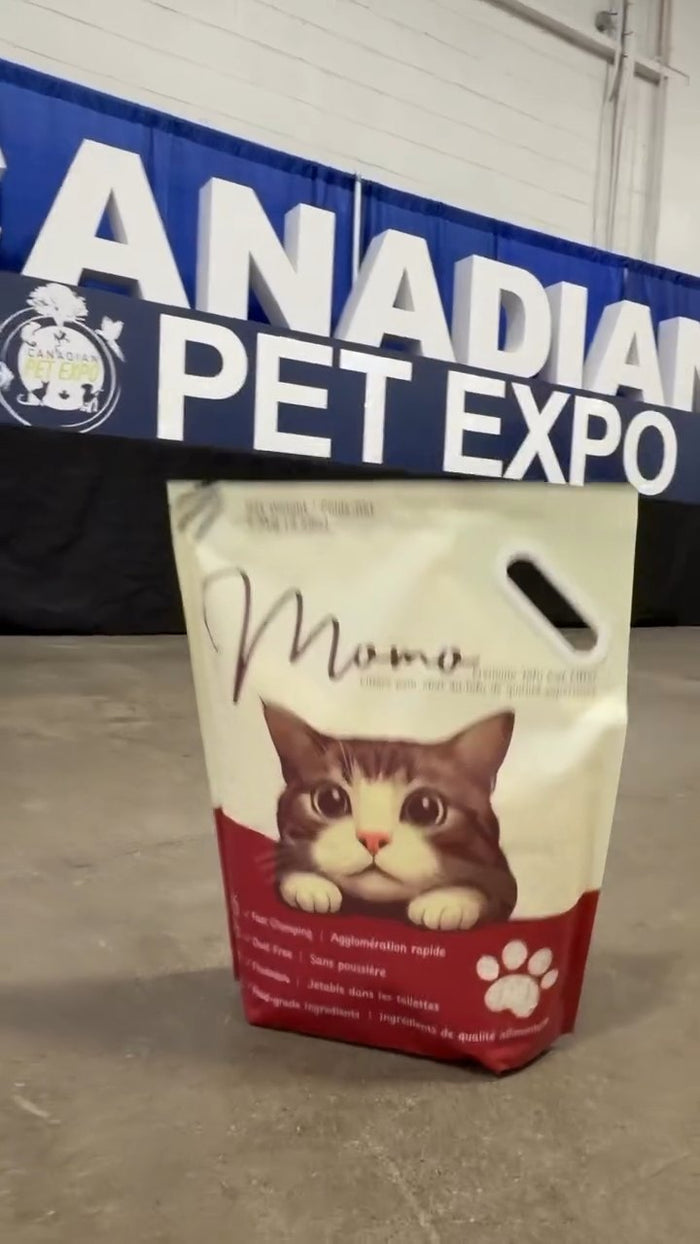 A bag of MOMOTO tofu litter in front of the Canadian Pet Expo banner